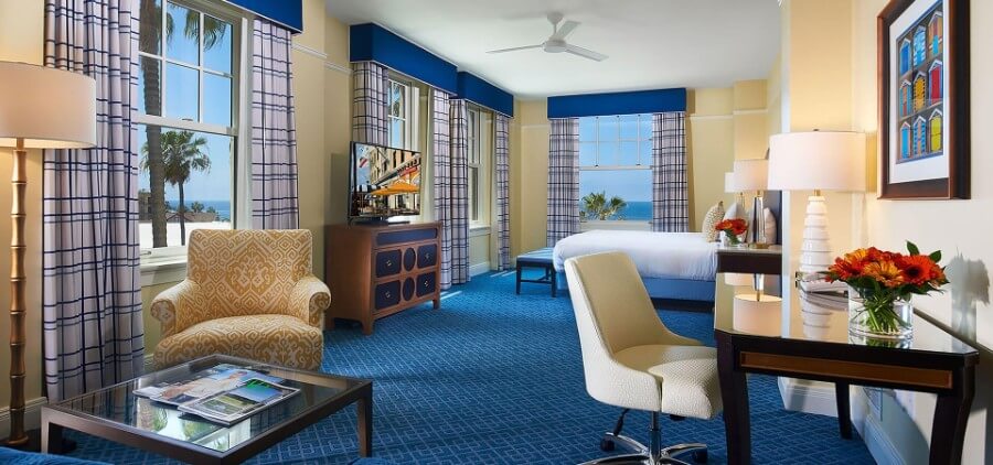 Inside plush guest room at Grande Colonial with blue carpet and expensive looking furniture