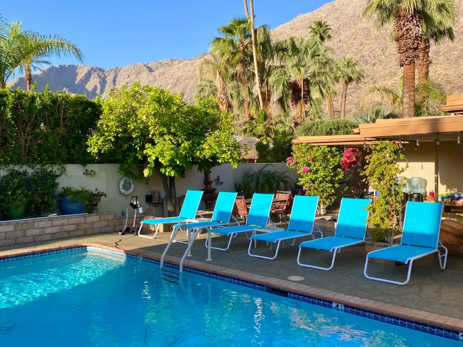 Hotel swimming pool with sunloungers in shade and rocky mountains behind