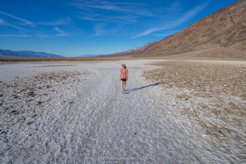 Woman walking on Badwater Basin salt crystals when dry on a hot day in california