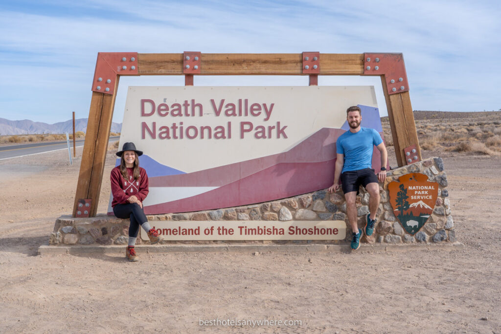 Mark and Kristen from Best Hotels Anywhere at either side of the Death Valley National Park welcome sign in California