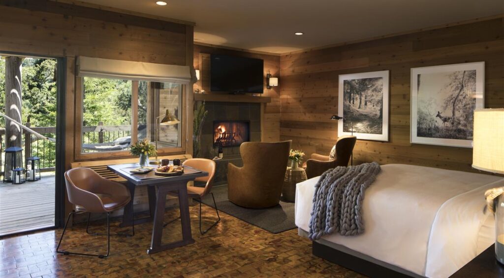 Alila Ventana is one of the most popular hotels in Big Sur CA with plush interior design wooden floor bed photos on wall and sofa leading to balcony