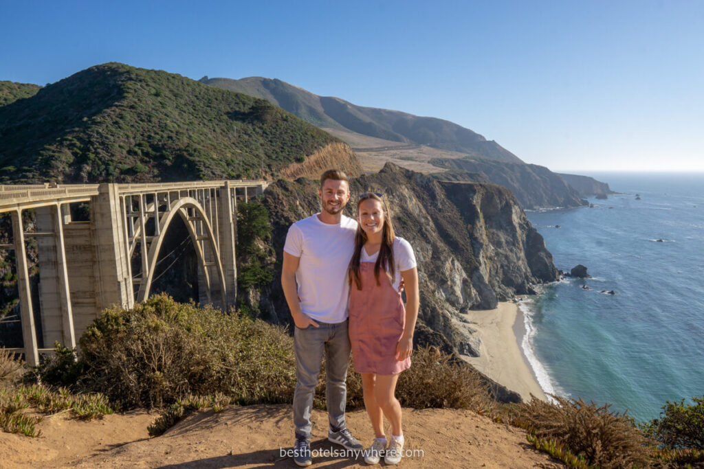 Mark and Kristen Morgan from Best Hotels Anywhere standing in front of Bixby Bridge on the Pacific Coast Highway near Big Sur with beach and ocean below