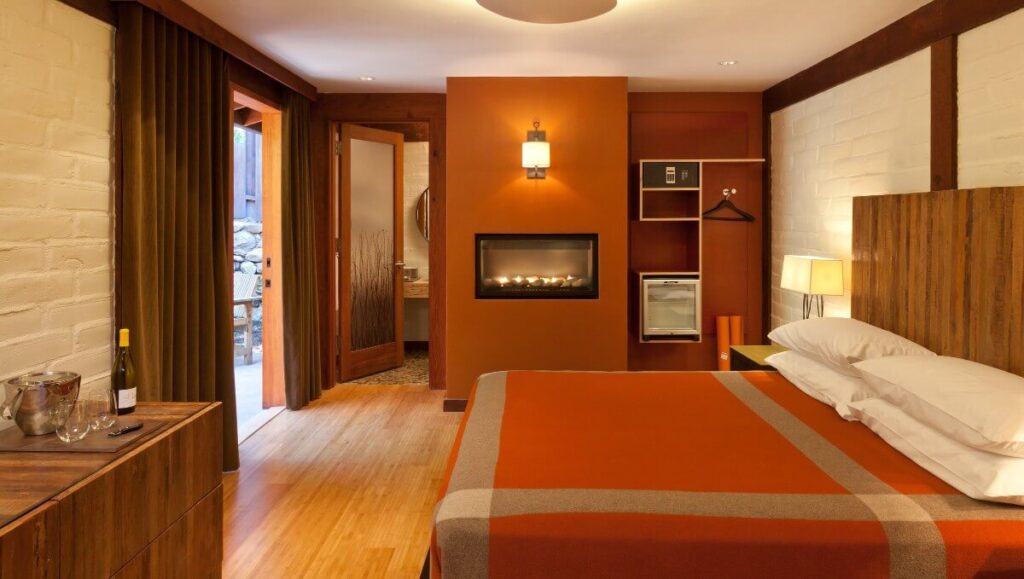 Plus bedroom with wooden floor huge bed fireplace in wall and lights on Glen Oaks Lodge hotels near Big Sur California