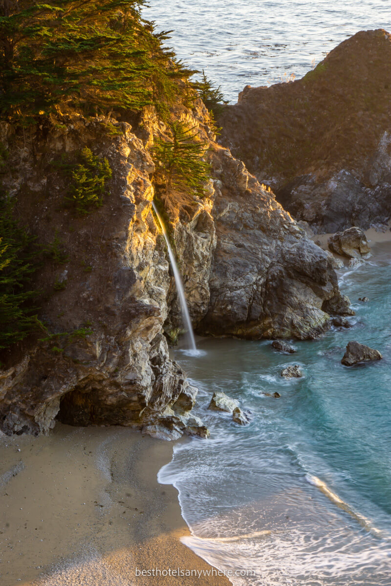 McWay Falls stunning waterfall wispy thin flowing into Pacific Ocean on sandy beach