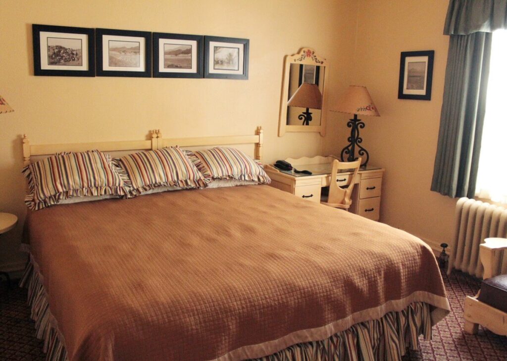 Large bed in a historic hotel with orange and tan colored furniture Lone Pine California