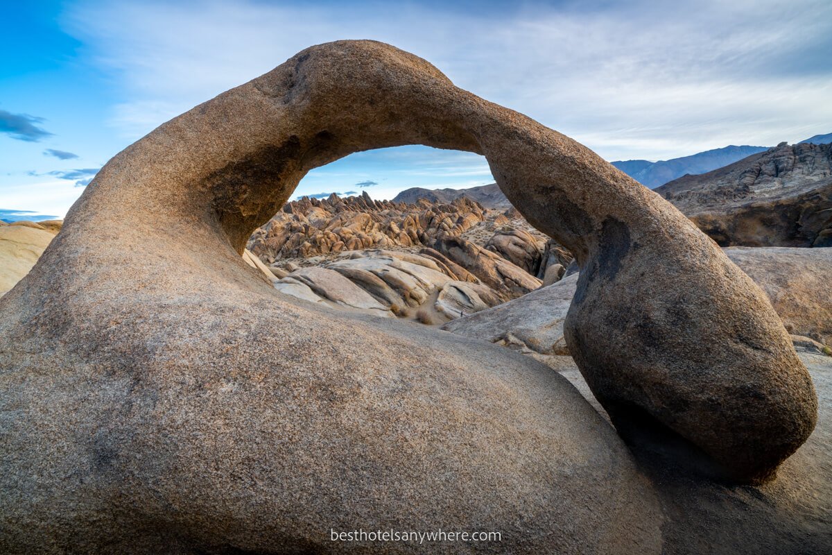 Mobius Arch in Alabama Hills a small but stunning and smooth arched rock formation with other rocks through the gap at dawn in California
