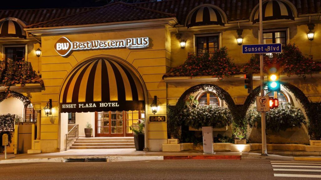 Exterior photo of Best Western Plus in West Hollywood at night with yellow and orange lights budget hotels in LA