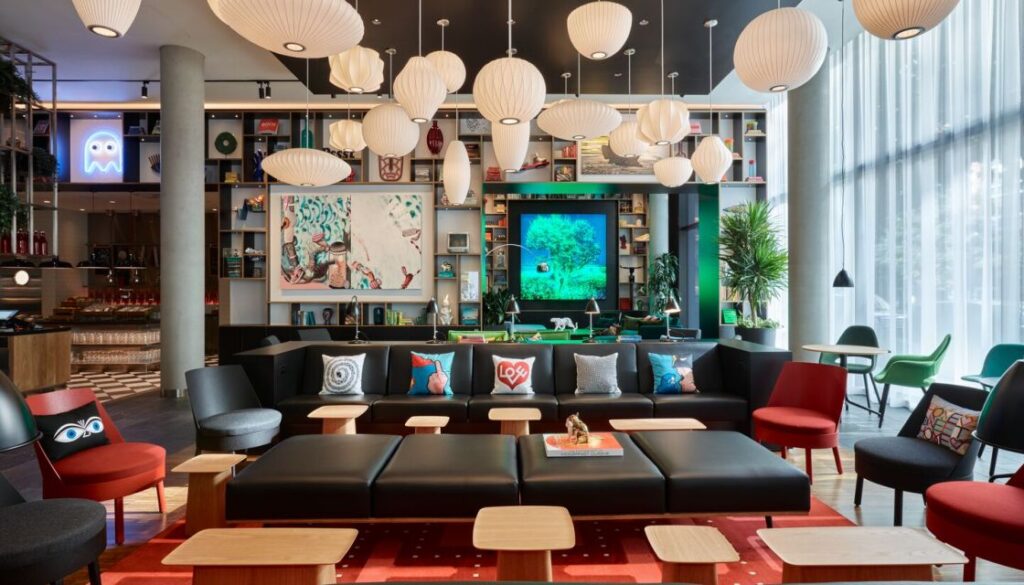Lounge area with sofas chairs lights and pillars all colored brightly inside a hotel lobby area CitizenM downtown Los Angeles