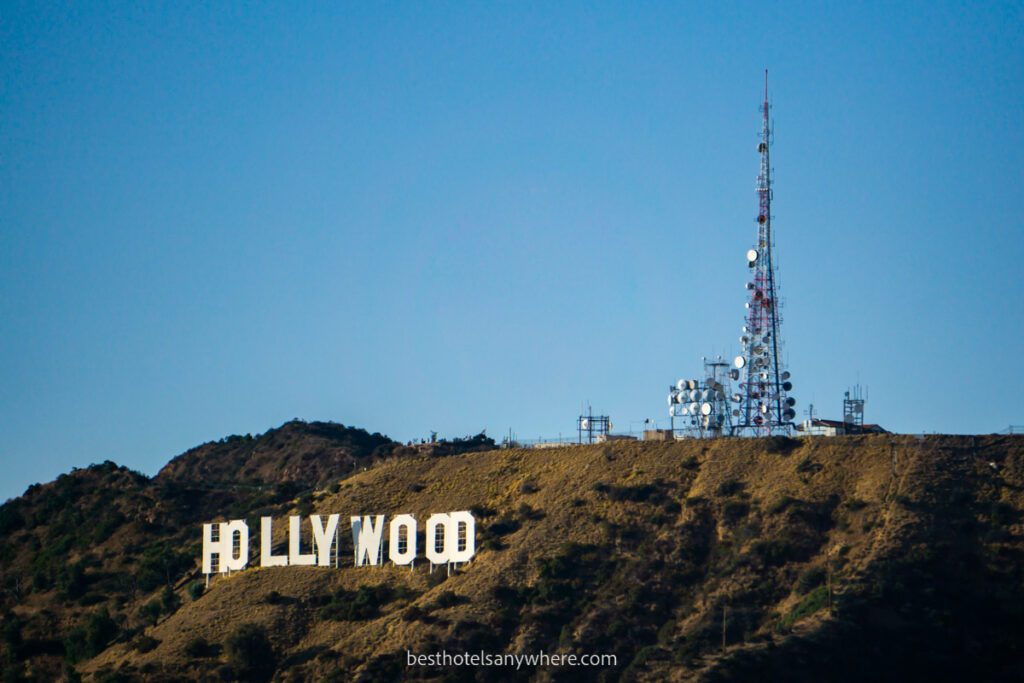 Hollywood sign on the mountainside with telecommunications tower behind and blue sky
