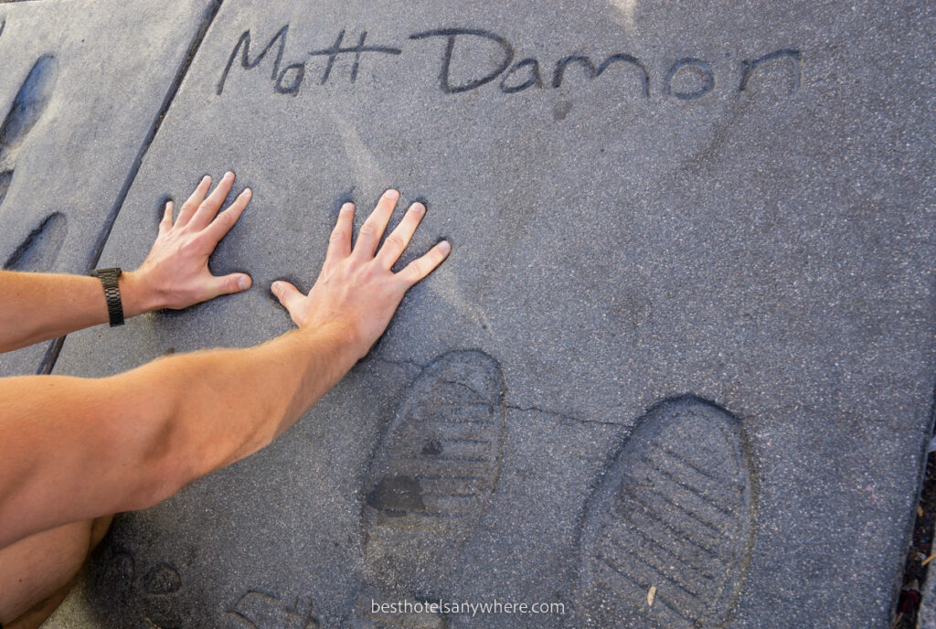 Man putting hands into hand prints left in concrete by a movie star in Hollywood LA