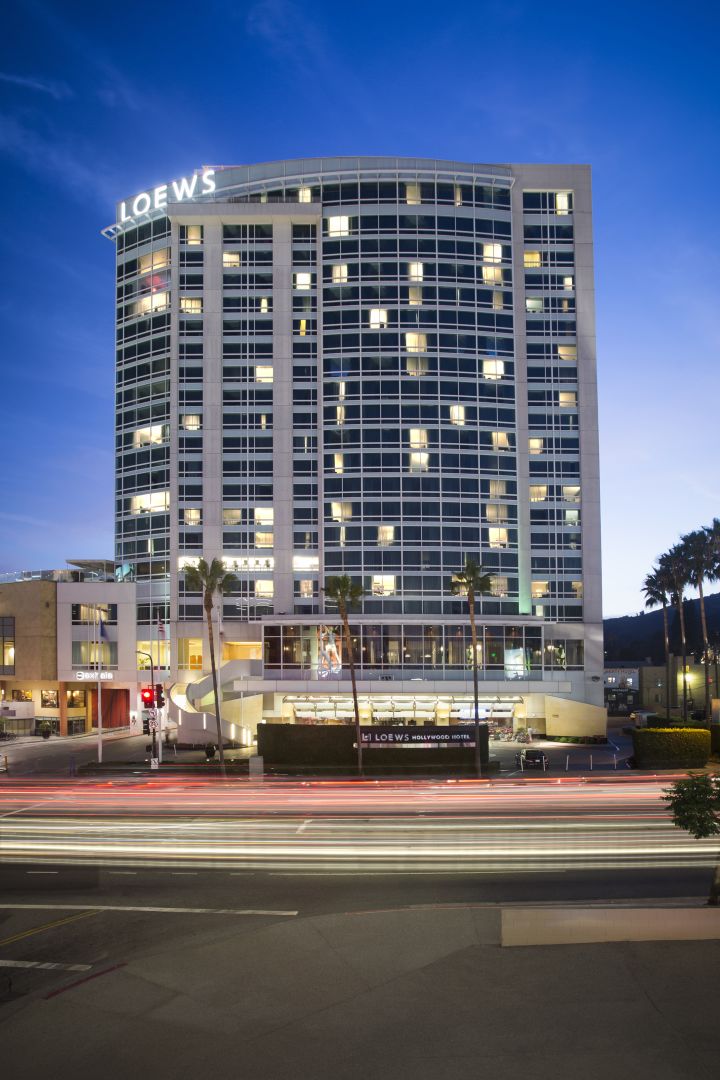 Exterior photo of Loews Hollywood lit up at night one of the popular Los Angeles hotels for budget travel