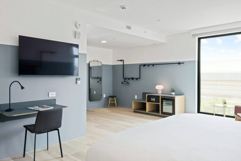 Clean minimalist guest room with bed tv and loads of open space leading to window letting light in one of the best hotels in downtown Los Angeles