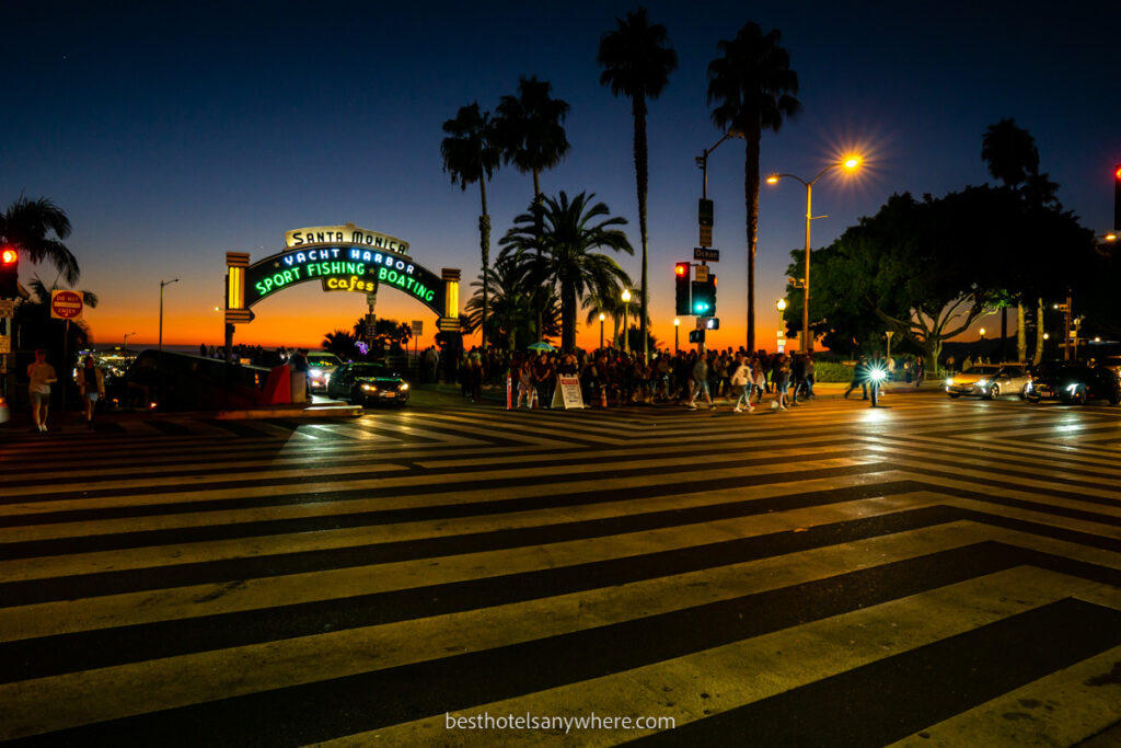 Santa Monica crosswalks four way with neon lights illuminating sign at sunset and stunning orange color on horizon