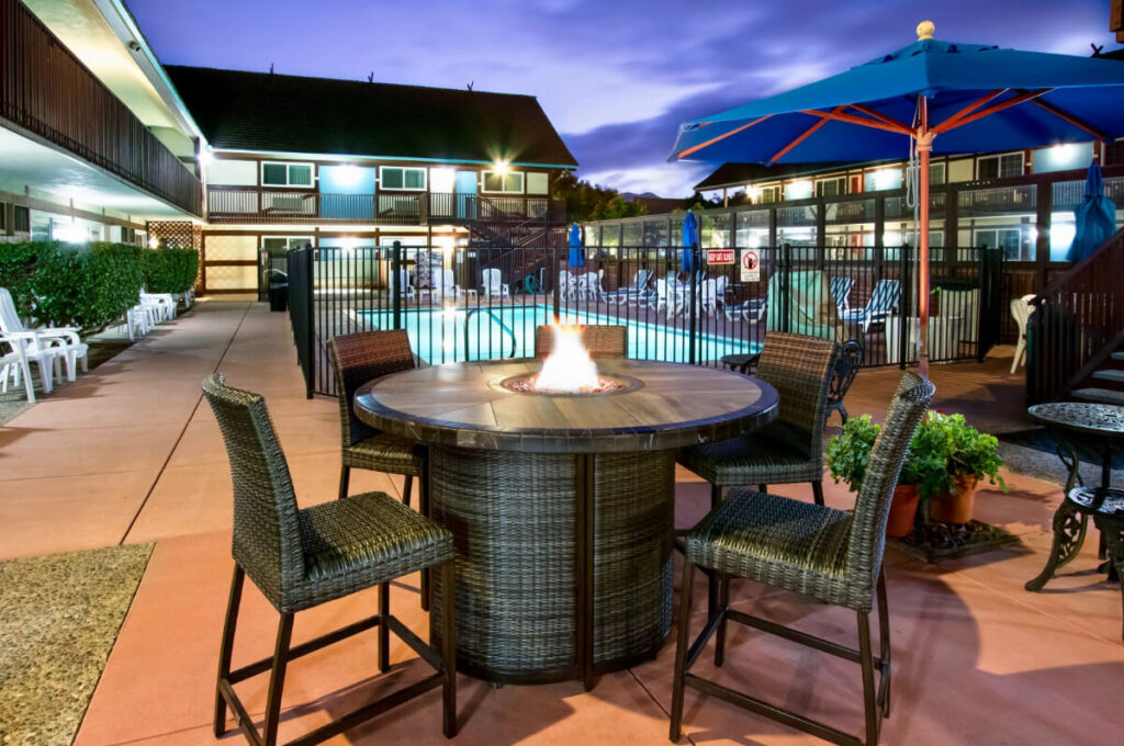 Fire pit and chairs with swimming pool and buildings lit up at dusk King Frederik one of the best hotels in Solvang CA