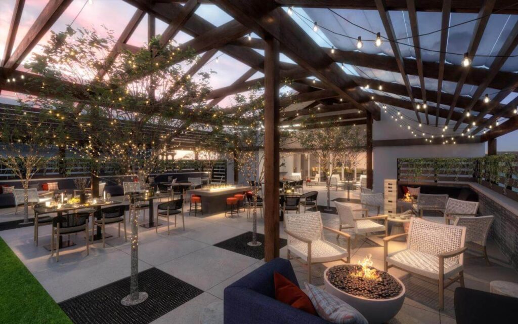 Outdoor communal area with chairs tables fire pits and wooden beams at dusk