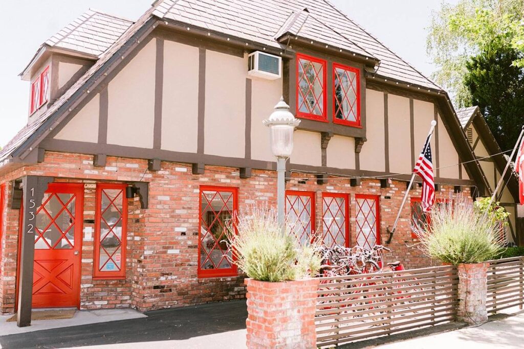 Hamlet Inn cheap top rated place to stay in Solvang exterior photo of hotel with red window and door frames