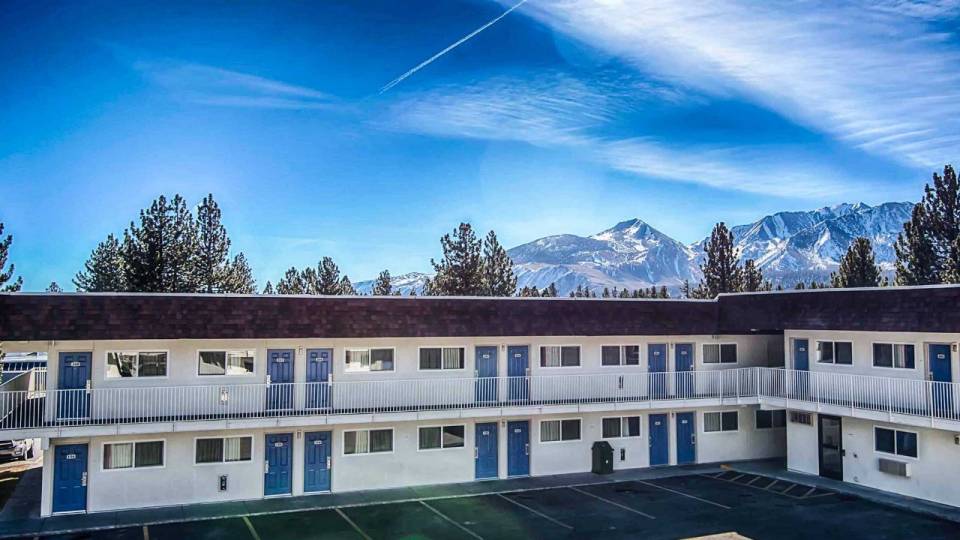 Motel 6 white painted wooden building with mountain views in distance cheapest hotels in Mammoth Lakes California