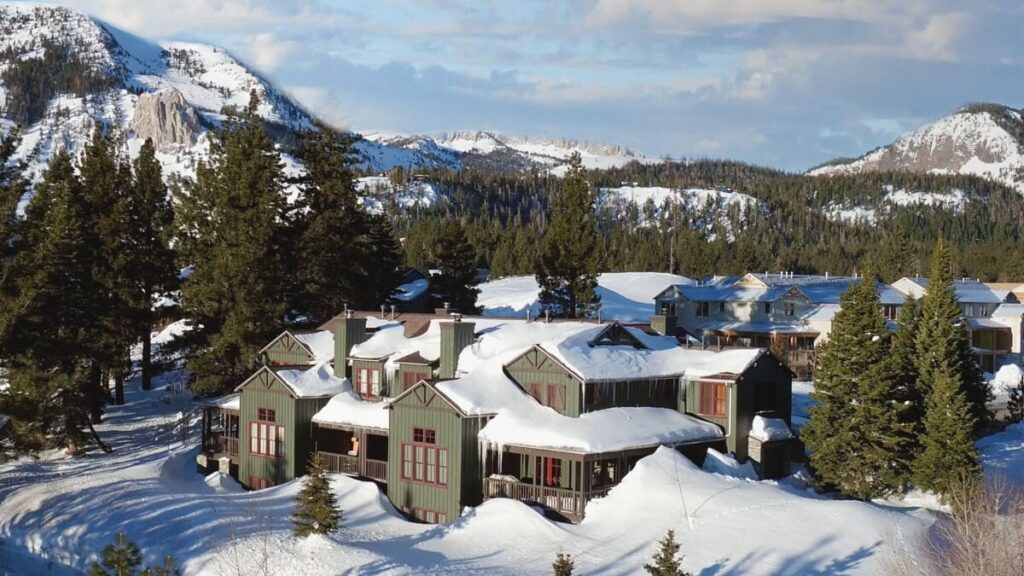 Building covered in snow with deep snow all around forest and mountains the Snowcreek Lodge hotel in mammoth lakes CA