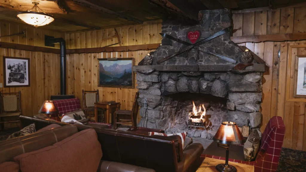 Stone fireplace with fire on and chairs surrounding Tamarack Lodge one of the best cheap hotels in Mammoth Lakes CA