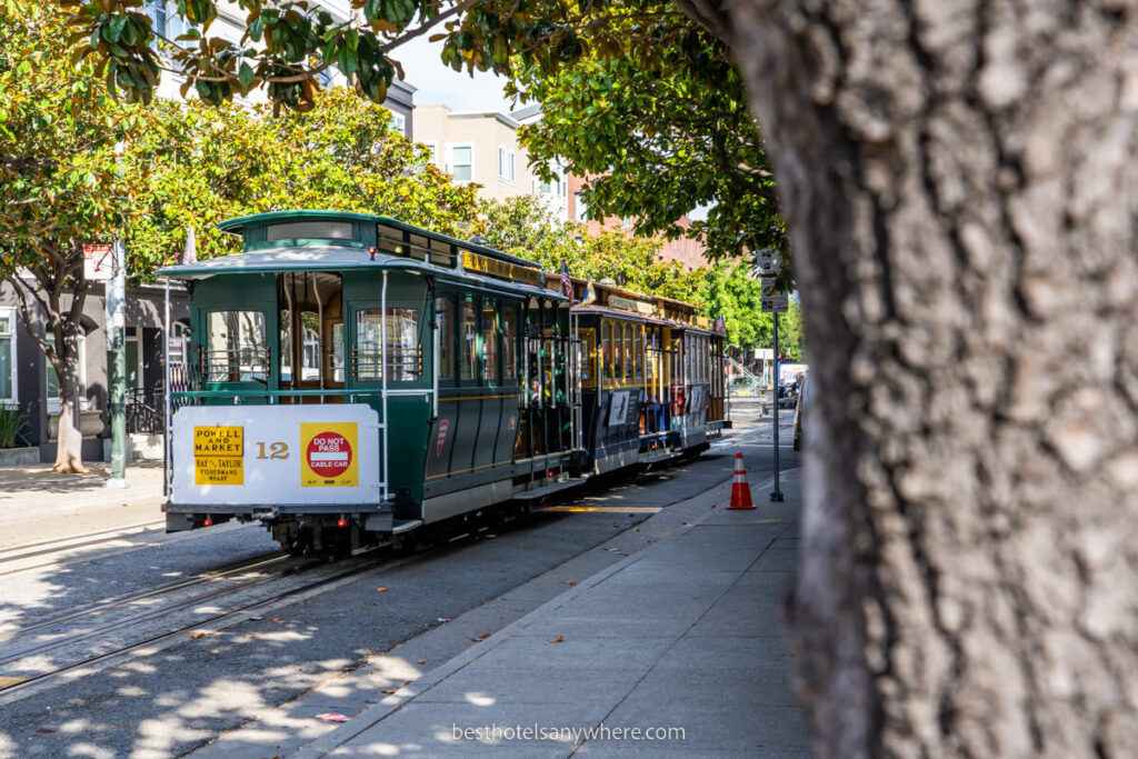 Cable Car on tram line next to a tree good idea to stay near a line at San Francisco hotels
