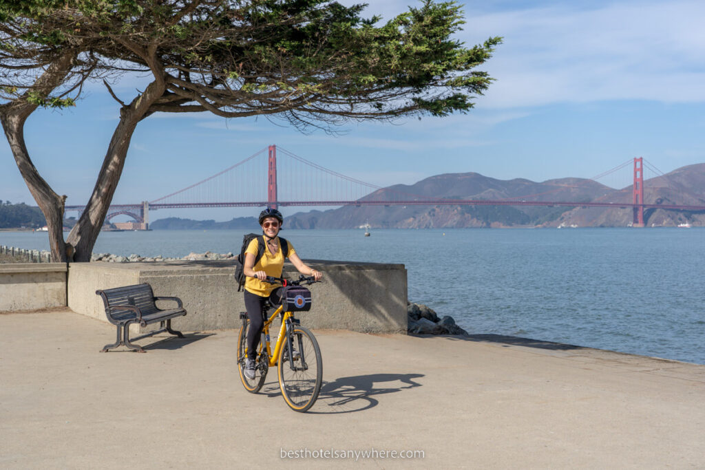 Kristen from Best Hotels Anywhere riding a bike next to SF bay with Golden Gate Bridge in background