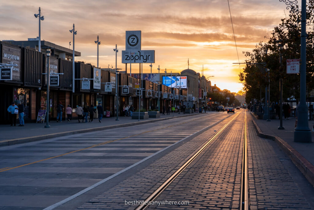 Tram tracks and low rise wooden shop buildings of Fisherman's Wharf at sunset Zephyr Hotel in San Francisco