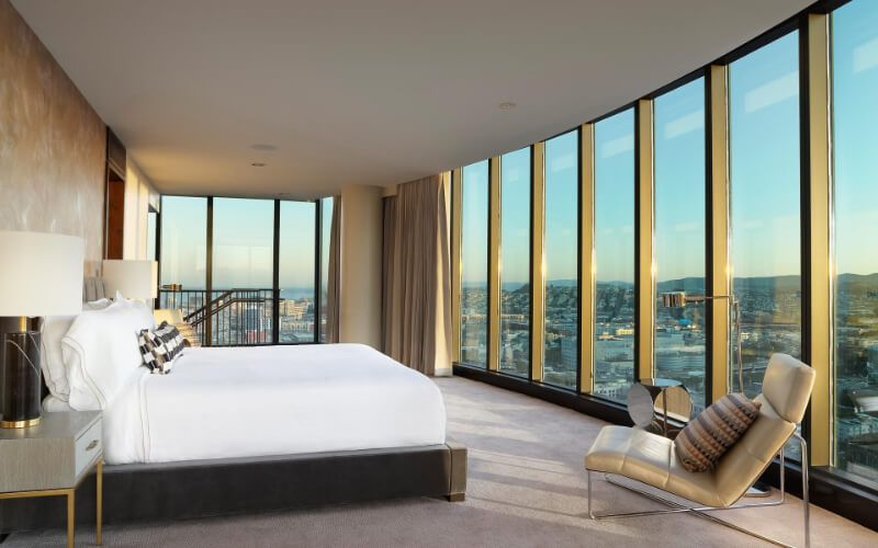 Large and very light guest room with huge floor to ceiling windows on two sides double bed and chair InterContinental Hotel in San Francisco