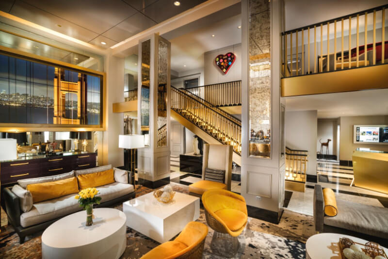 Interior of Staypineapple Hotel in San Francisco with yellow furniture and decor tables chairs stairs in large open plan room