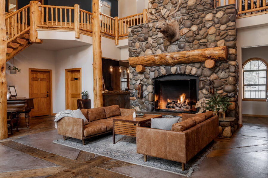 Lodge interior with sofa open fireplace stone chimney and wooden bannister