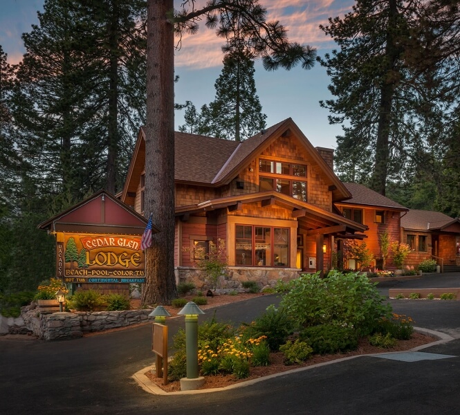 Cedar Glen Lodge one of the top rated hotels in North Lake Tahoe exterior photo of wooden building and sign lit up at dusk