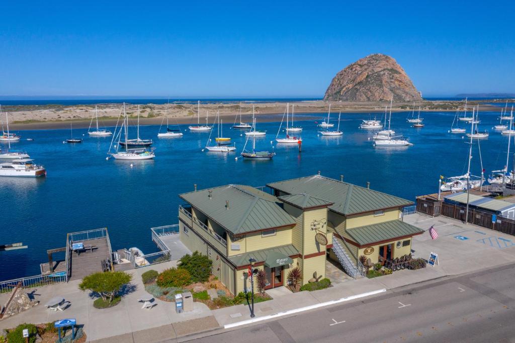 Yellow colored building on the waterfront with marina and huge rock in distance Estero Inn one of the top rated hotels in Morro Bay CA