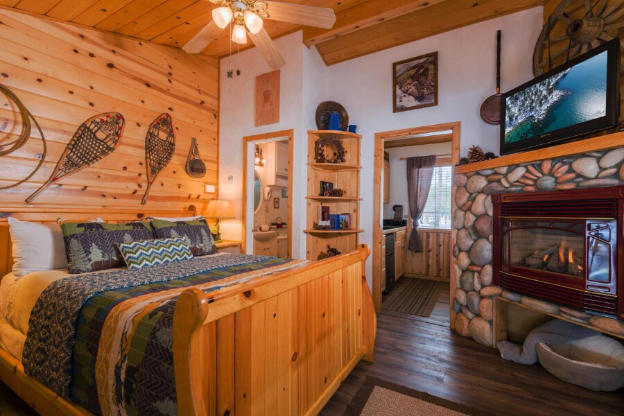 Wooden bed frame open fireplace and cozy decor in a wooden lodge