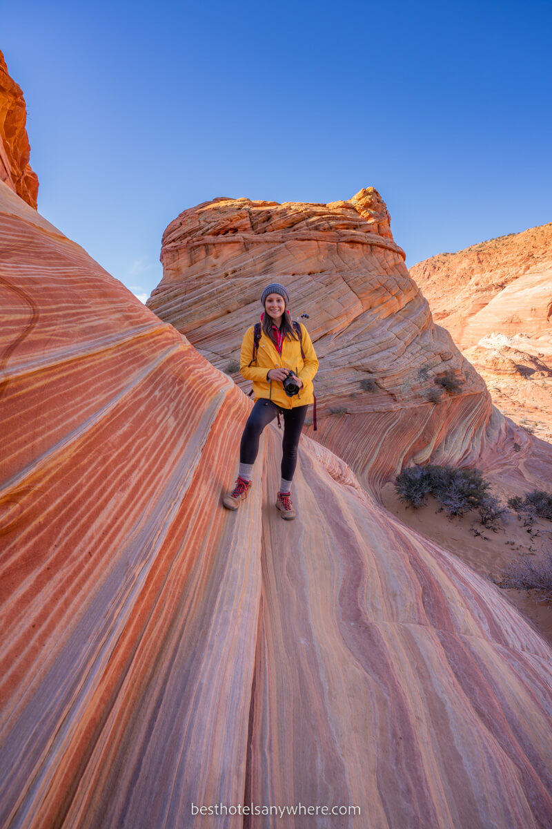 Hiker with camera in a coat stood on swirling patterned rock formations in north coyote buttes