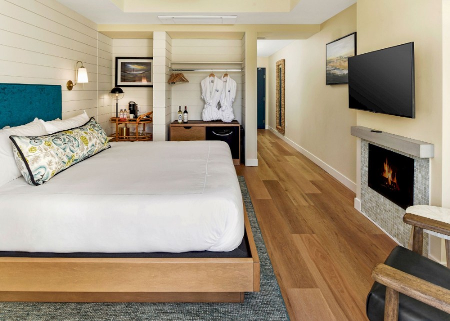 Guest bedroom with fireplace tv bath robes and wooden floor at Inn At Rose's Landing a top rated Morro Bay CA hotel