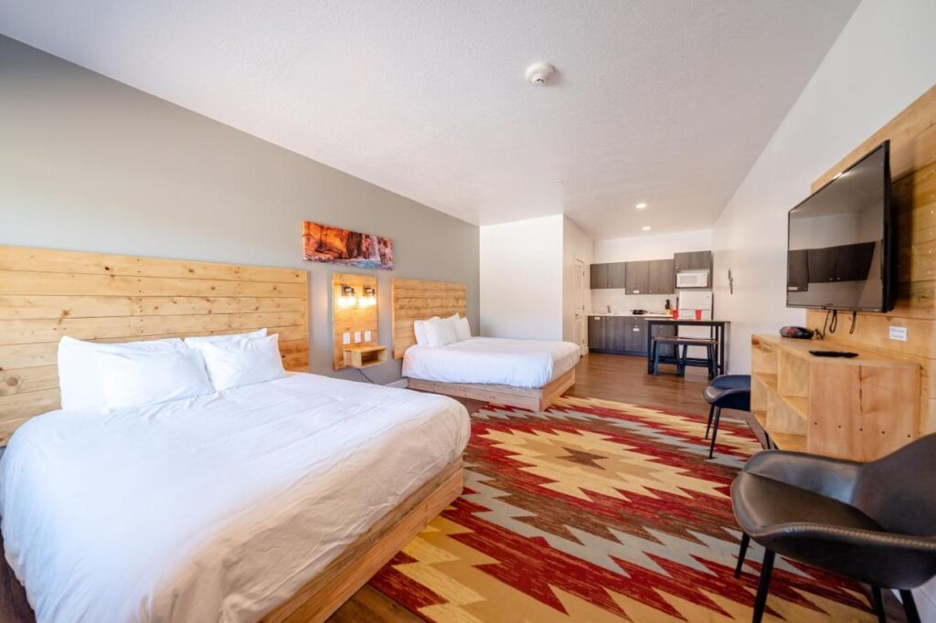 Guest bedroom with two beds carpet and kitchenette suites in a Kanab Utah hotel