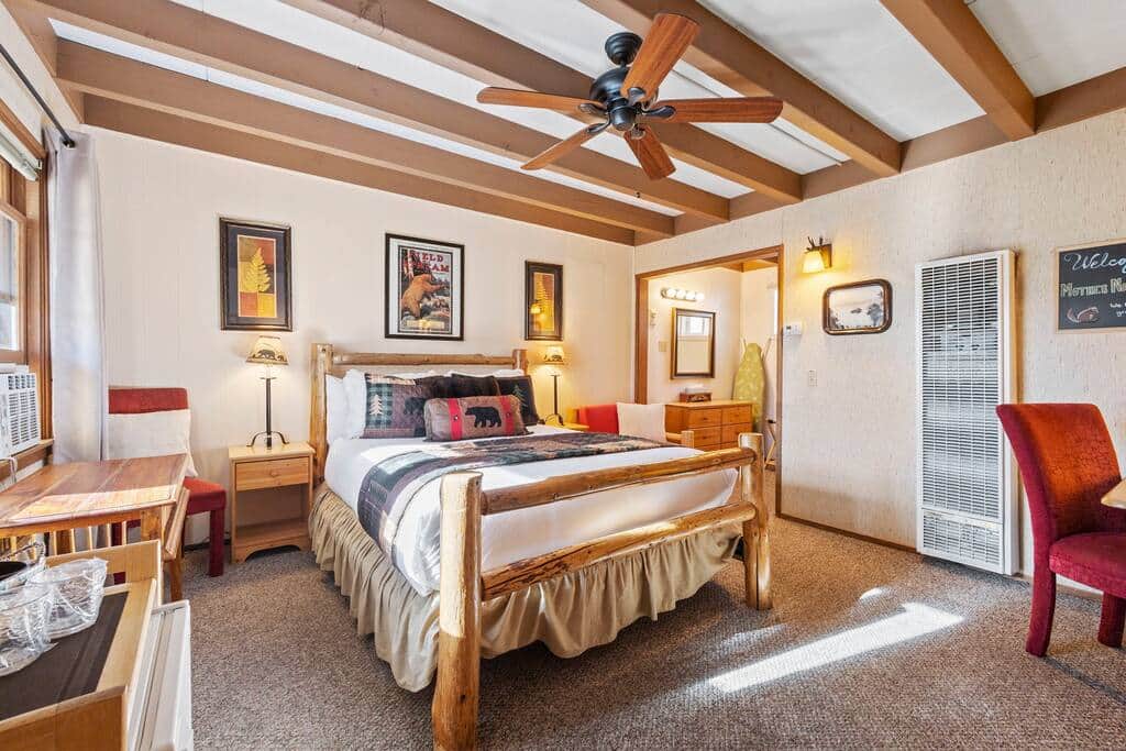Guest bedroom with beams and wooden bed frame at Mother Nature's Inn hotel in Tahoe City CA