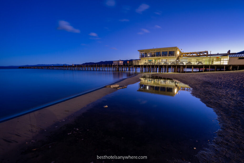 Pier and boathouse on a beach in South Lake Tahoe CA at twilight with deep blue water and sky