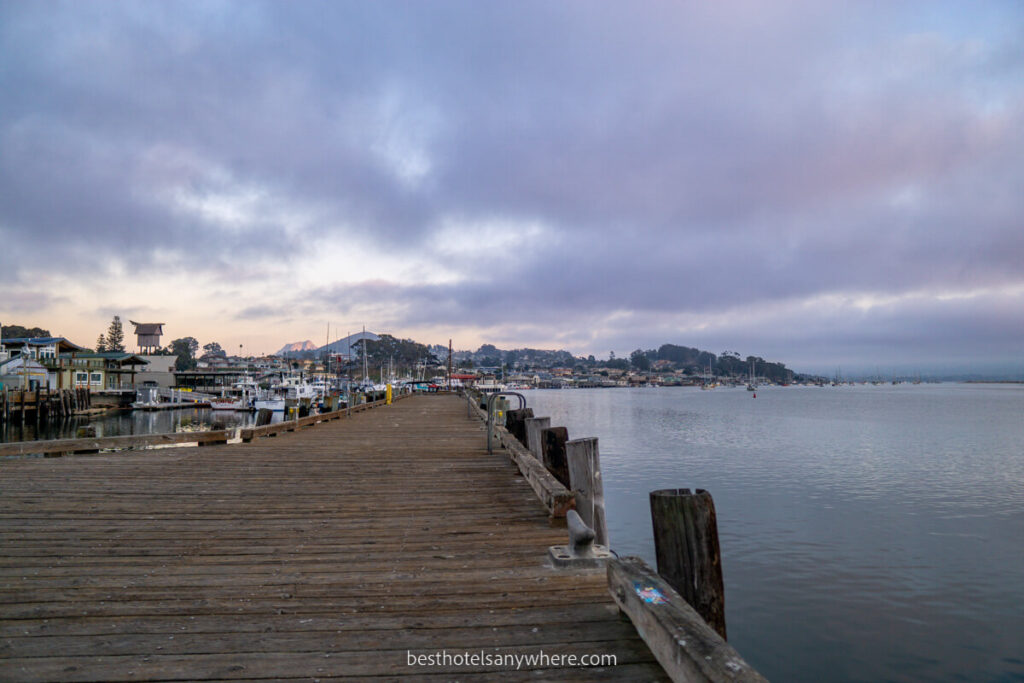 Wooden pier next to an ocean inlet with colorful clouds at sunset in Morro Bay California