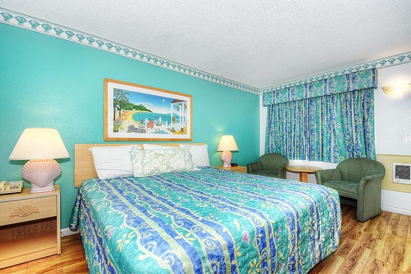 Guest bedroom with bright green duvet covers on a wooden floor