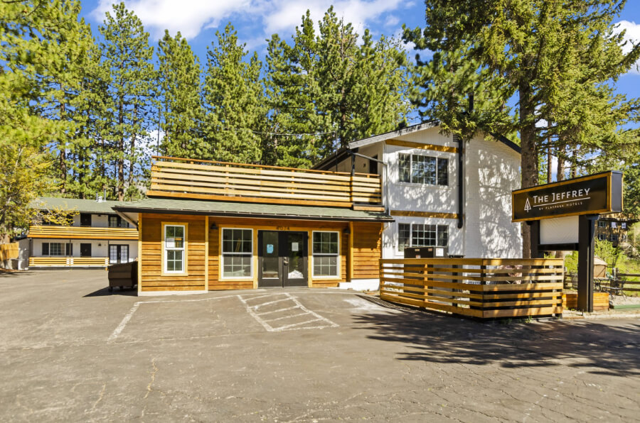 Yellow and white wooden painted building with car park and green trees lodging in South Lake Tahoe