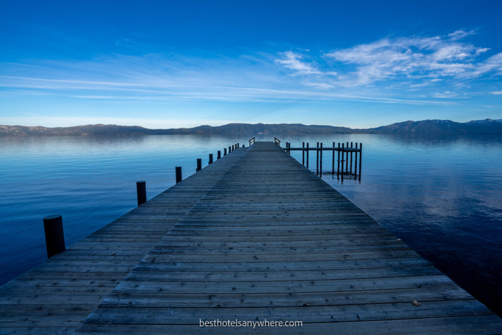 Wooden pier bursting out into Lake Tahoe at dawn with blue water and blue sky