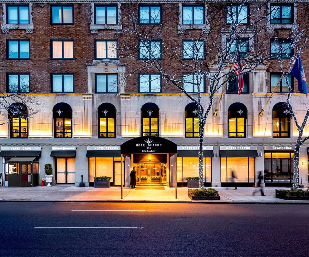 Exterior photo of the entrance and front side of Hotel Beacon in New York City at dusk with lights on