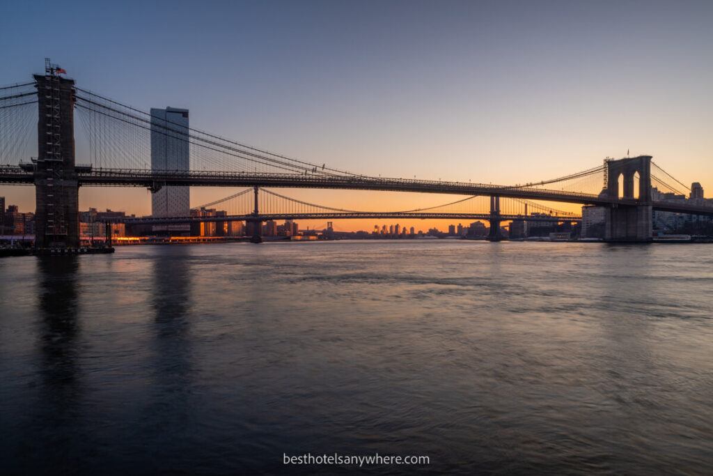 Brooklyn Bridge at sunrise with orange sky as seen from Pier 17 in NYC