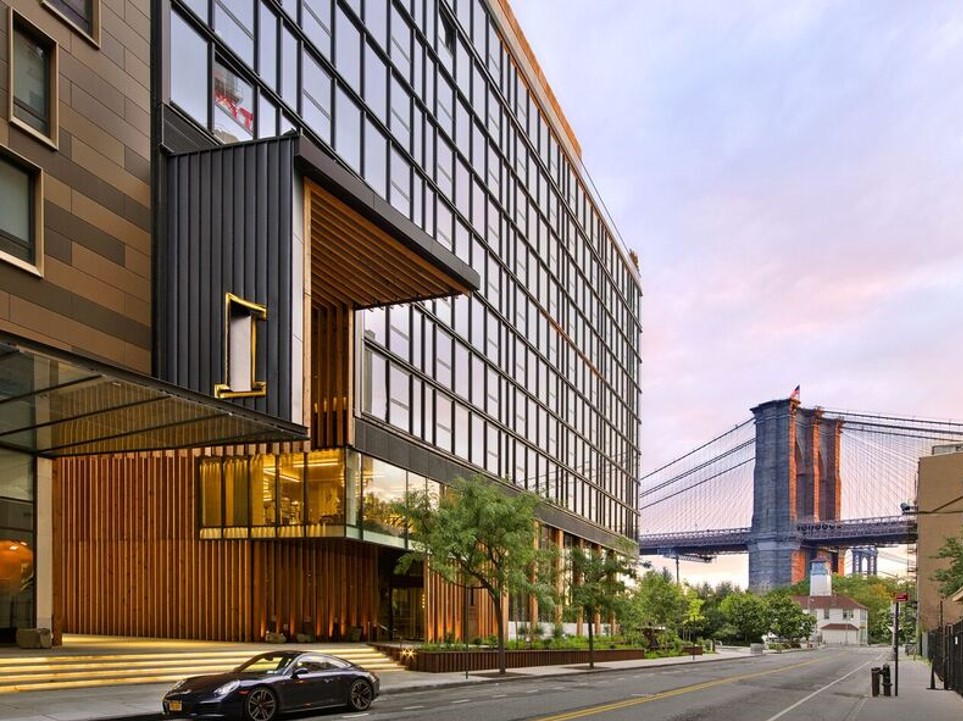 Tall building with glass windows and Brooklyn Bridge in background