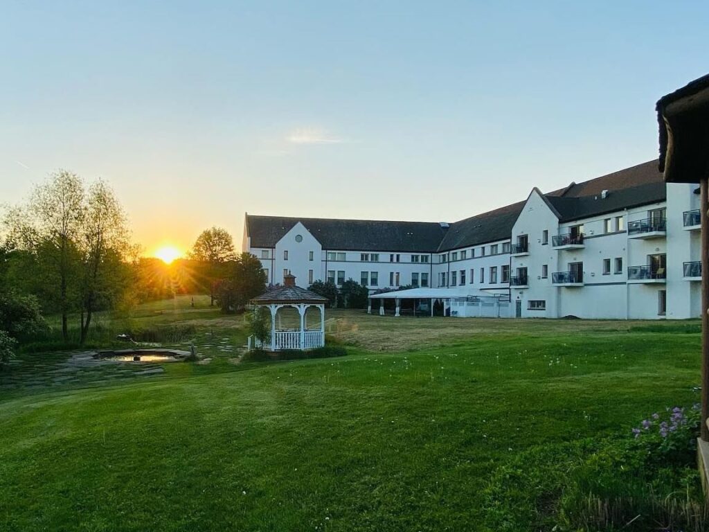Sunset over a hotel and spa set in grounds with large green lawn