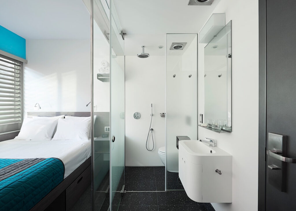 Pod style guest accommodation in New York with small bed and clean looking shower