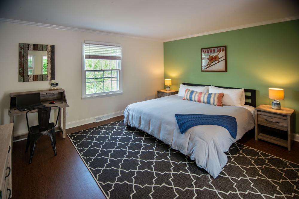 Inside a guest bedroom with queen bed and patterned rug