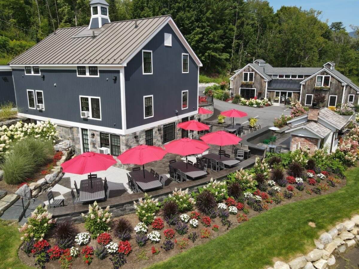 Exterior photo of a building with tables, chairs and a garden on a sunny day in Vermont