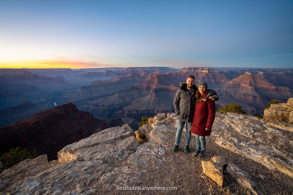 Mark and Kristen Morgans from Best Hotels Anywhere standing together on the edge of Grand Canyon South Rim at sunset