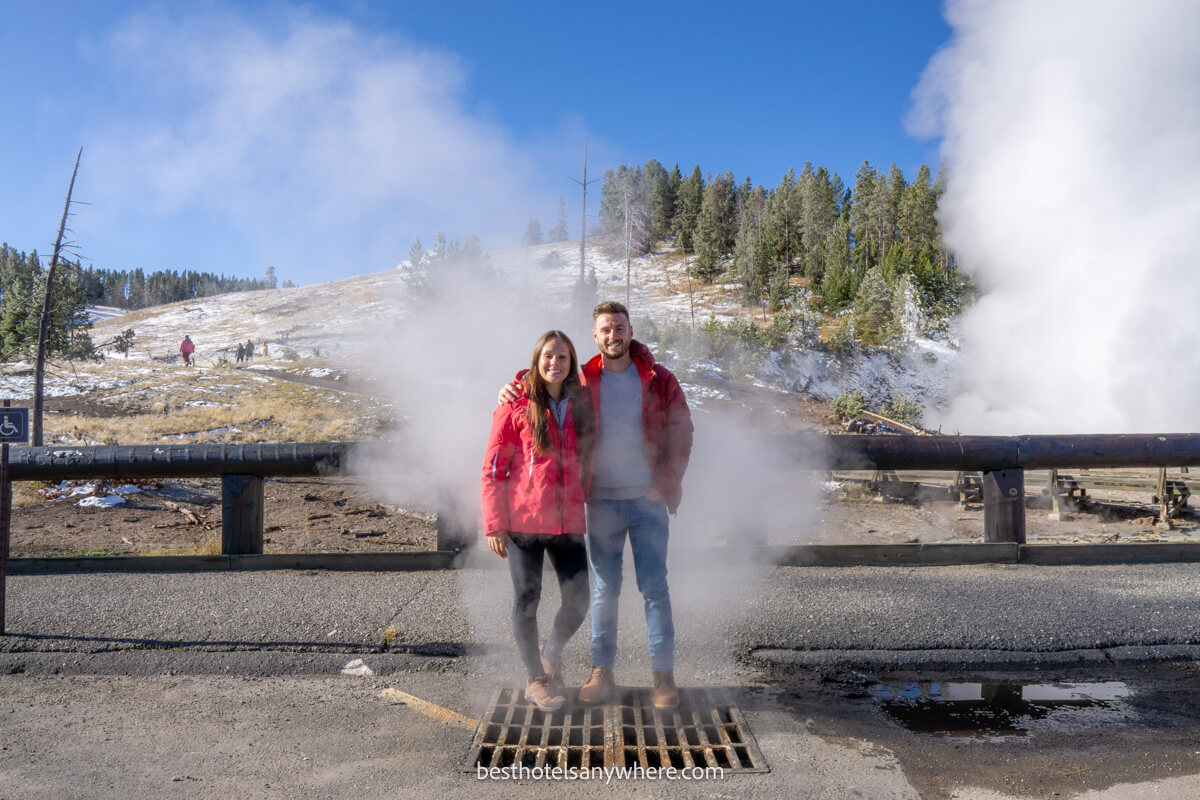 Mark and Kristen Morgan from Best Hotels Anywhere standing on a metal vent with steam billowing out from volcanic caldera Yellowstone